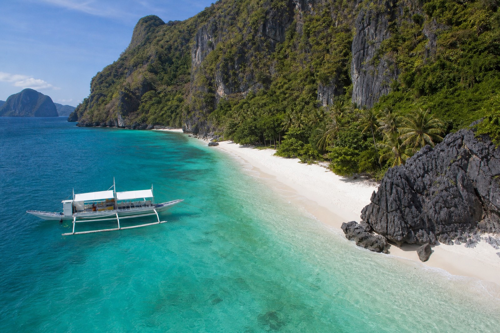 A karst-framed cove of turquoise water and pale sand in the Bacuit Archipelago off El Nido