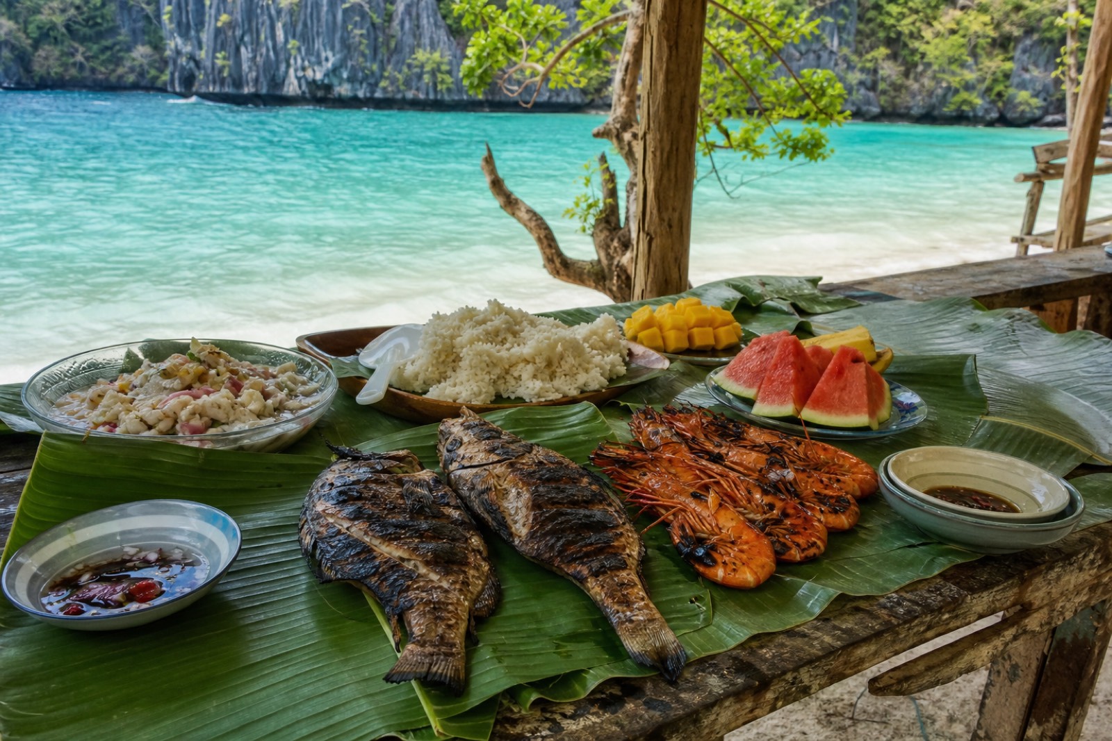 A beach buffet lunch of grilled fish, meat, rice and tropical fruit laid out during an El Nido island-hopping tour